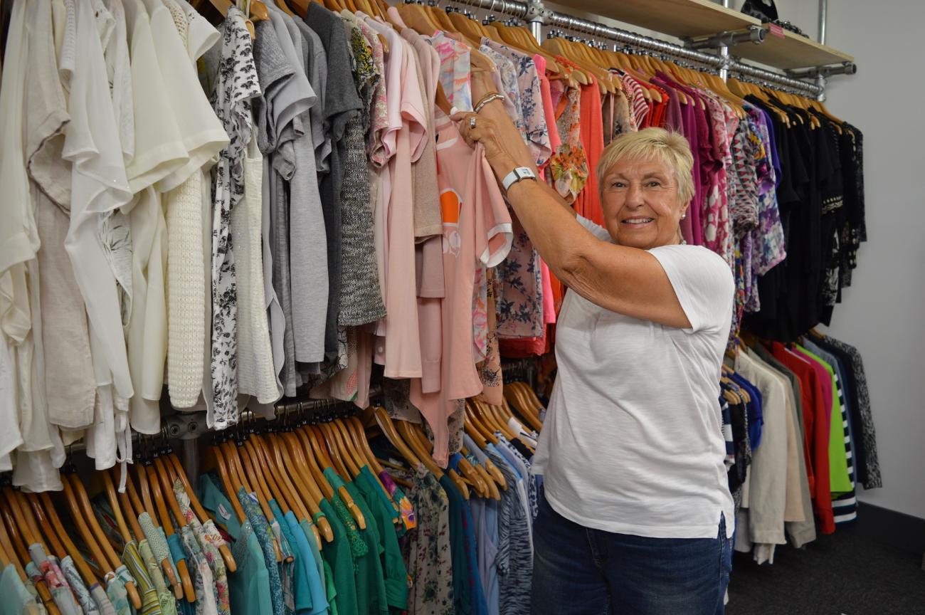 Julia's House shop volunteer Shelagh hangs-up clothes