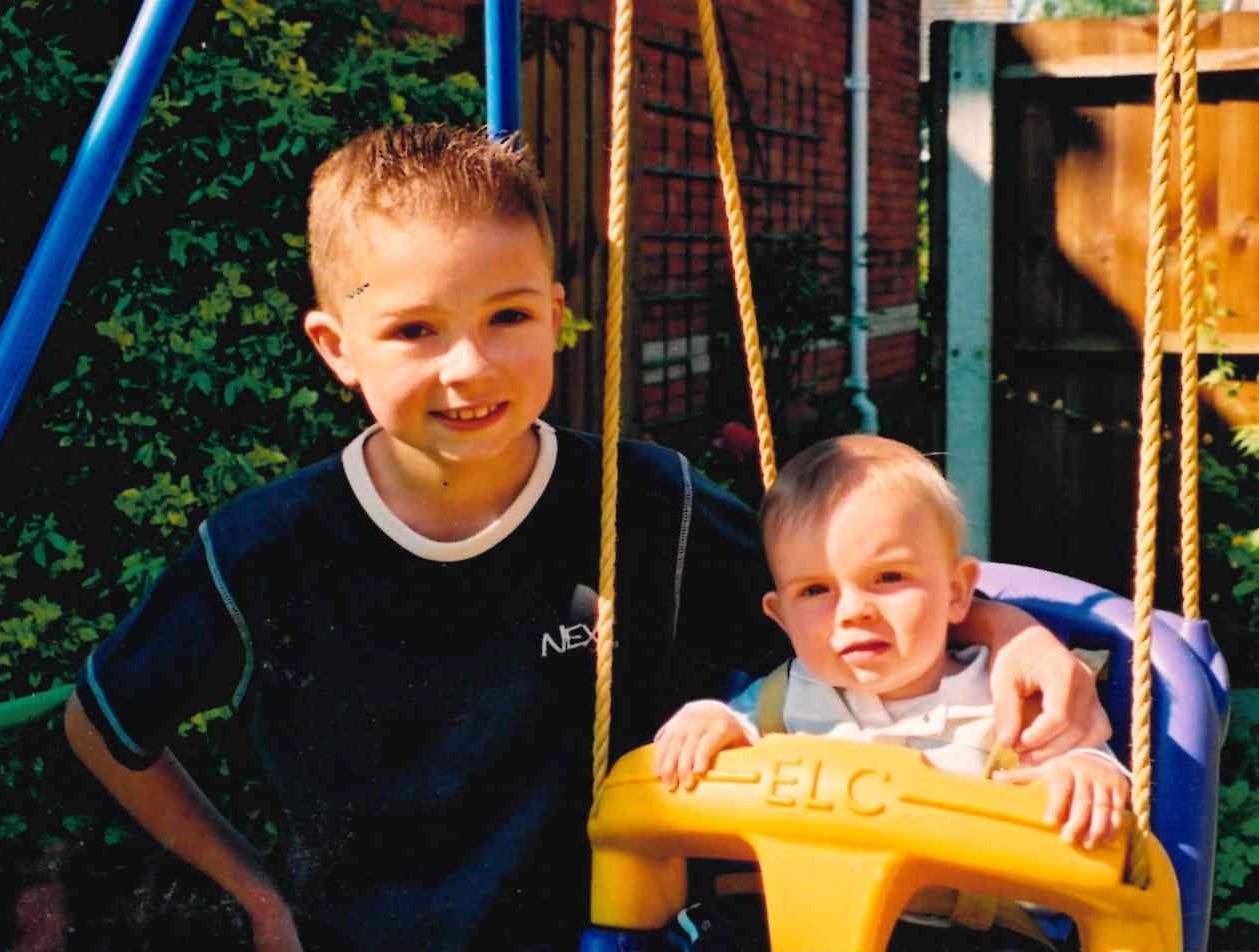 Sam Waters smiles with brother Matthew who is in a swing